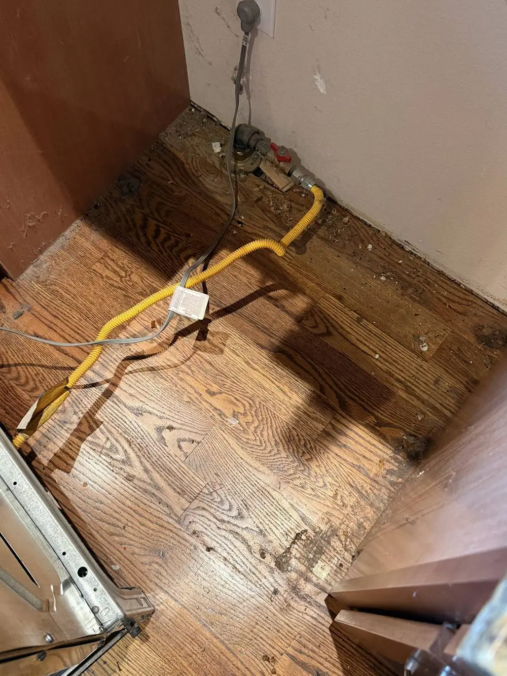 Floor and baseboards behind an appliance reached during an L&G Cleaning deep clean